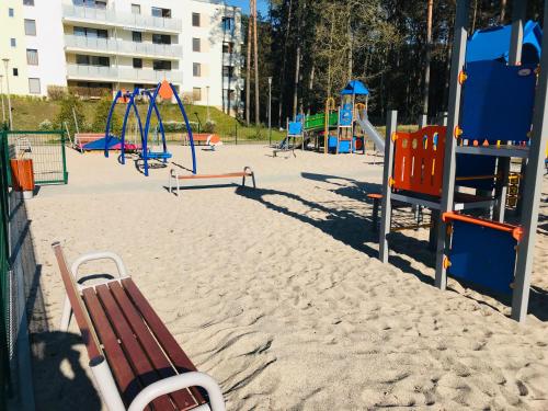a playground with chairs and playground equipment in the sand at AQUAMARINA ONYX GOLD in Międzyzdroje