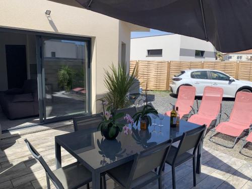 ル・グロー・ダグドにあるAppartement de 2 chambres a Agde a 200 m de la plage avec jardin clos et wifiのダイニングテーブル(ピンクの椅子、パラソル付)