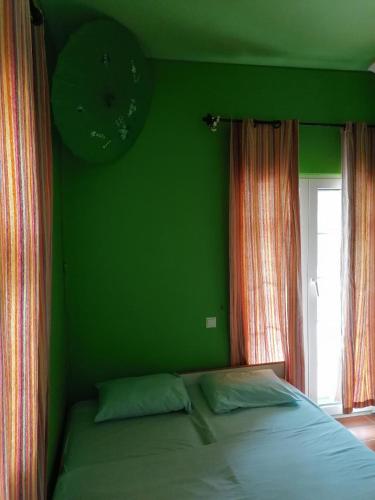 a green bedroom with a bed and a clock on the wall at Ευχάριστη βίλα στη Χαλκίδα στην περιοχή ''Αλυκές'' in Chalkida