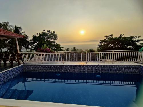 a swimming pool with a sunset in the background at WhiteHouse Homestay by Oxystays Hospitality in Alibaug