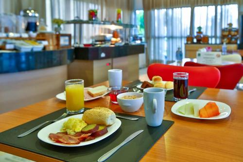 a table with plates of breakfast food on a tray at Quality Rio de Janeiro - Barra da Tijuca in Rio de Janeiro