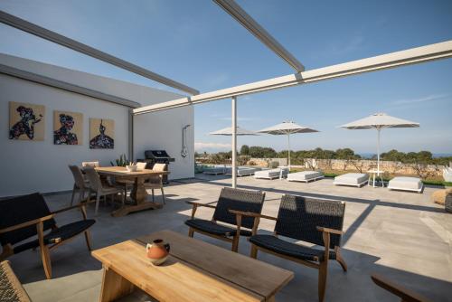 a patio with tables and chairs and large windows at Margaret Villa - Pool, Heated Spa Whirlpool & BBQ, By ThinkVilla in Angeliana