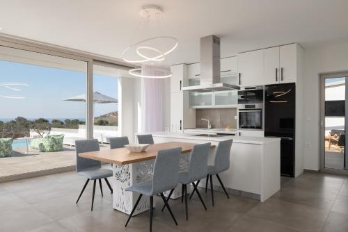 a kitchen with a wooden table and chairs and a large window at Margaret Villa - Pool, Heated Spa Whirlpool & BBQ, By ThinkVilla in Angeliana