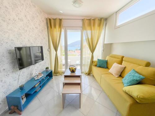 a living room with a yellow couch and a tv at Al Mare in Igalo