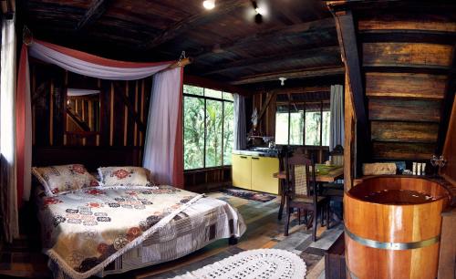 a bedroom with a bed and a desk and a table at Chalé Itape in Guabiruba