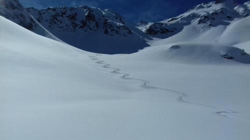 un sentier dans la neige avec une montagne en arrière-plan dans l'établissement Auberge du Glandon, à Saint-Colomban-des-Villards