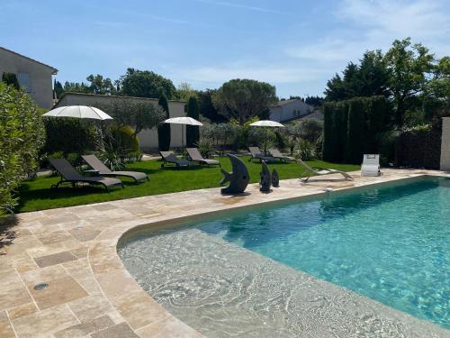 uma piscina com cadeiras e guarda-sóis num quintal em Mas Beau Soleil & Spa Gîtes de Charme avec Jacuzzi Privé em Saint-Rémy-de-Provence