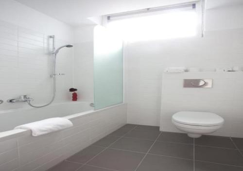 a white toilet sitting next to a shower in a bathroom at Century Hotel Antwerpen Centrum in Antwerp