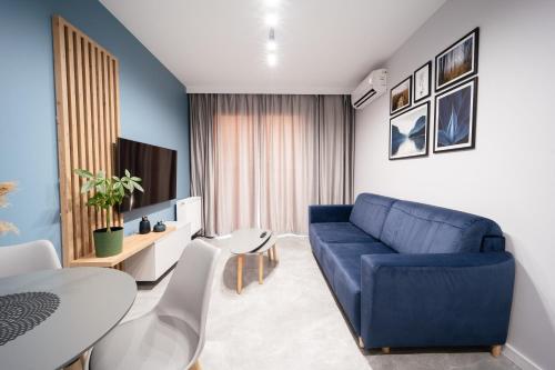 a living room with a blue couch and a table at Apartament Ogrody Centrum in Bielsko-Biała