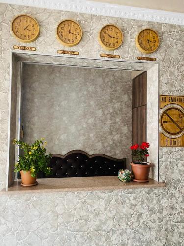 a mirror with clocks on a wall with plants at Har-Mar Hotel in Goris
