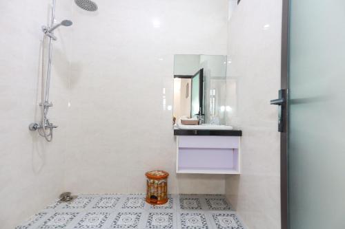 Baño blanco con lavabo y espejo en Học Hương Hotel Quy Nhơn en Quy Nhon