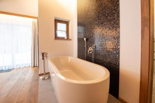 a bath tub in a bathroom with a tile wall at Chalet Hochkrimml 43 in Krimml