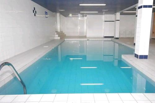a large swimming pool with blue water in a building at Ons Strandhuis in IJmuiden
