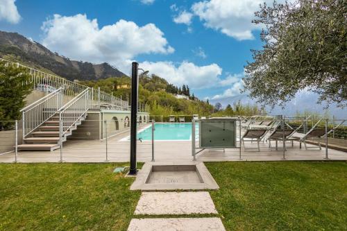 a swimming pool with chairs and stairs next to a building at Residence La Villa Tesoro in Tignale