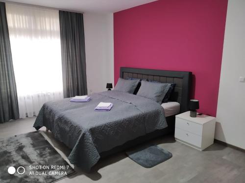 a bedroom with a bed and a purple wall at Markaz Apartman Bihać 2 in Bihać