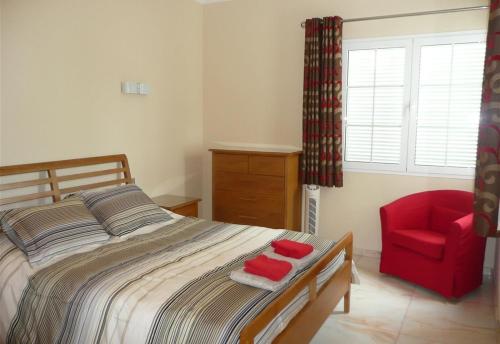 een slaapkamer met een bed en een rode stoel bij Villa Loretta in Puerto del Carmen