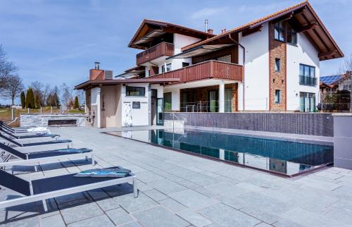 una casa con piscina al lado de un edificio en FOR MOMENTS Apartments & Spa, en Rosshaupten