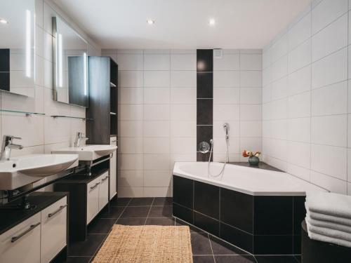 un baño con bañera y dos lavabos en Residence Kristall by VAYA inklusive Joker Card, en Saalbach Hinterglemm