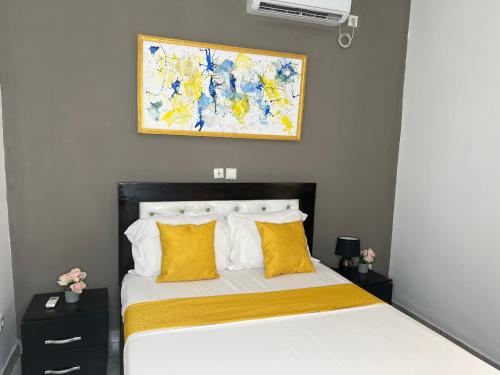 a bedroom with a bed with yellow pillows and a painting at Studio de haut standing, Bonamoussadi (Kotto) in Douala