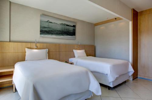 two beds in a hotel room with white sheets at Quality Rio de Janeiro - Barra da Tijuca in Rio de Janeiro