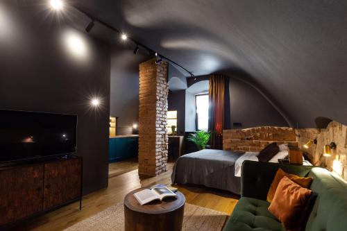 Habitación con cama, TV y sofá. en #stayhere - Historic Vilnius Old Town Chic Studio en Vilna
