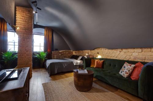a living room with a green couch and a brick wall at #stayhere - Historic Vilnius Old Town Chic Studio in Vilnius