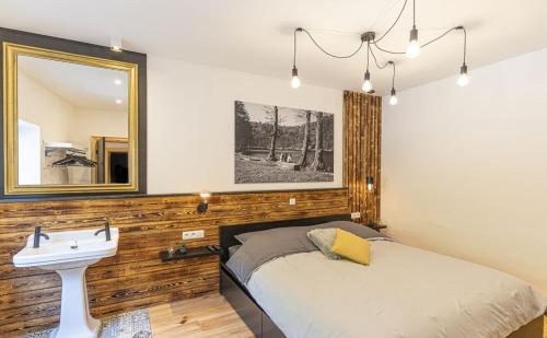 a bedroom with a bed and a mirror and a sink at Le Gîte des Platanes in Spa