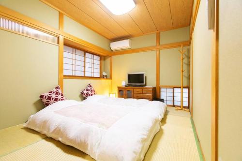 ein Schlafzimmer mit einem großen weißen Bett und einem TV in der Unterkunft KYO SAKURA HOUSE in Kyoto