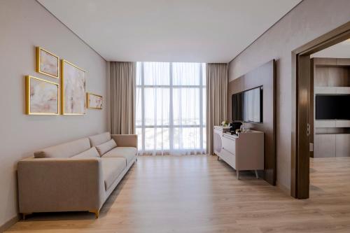 a living room with a couch and a television at Movenpick Jumeirah Village Triangle in Dubai