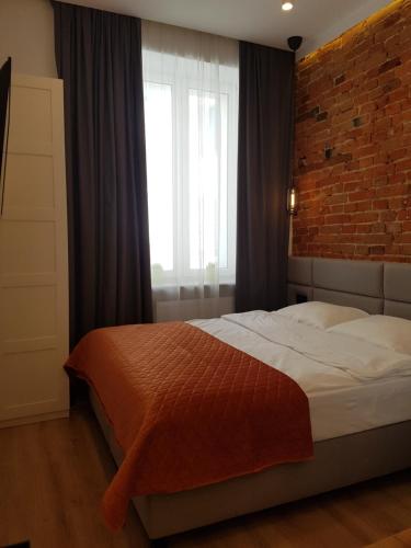 a bedroom with a bed and a brick wall at BOOGIE Home Kamienica Łódzka in Łódź