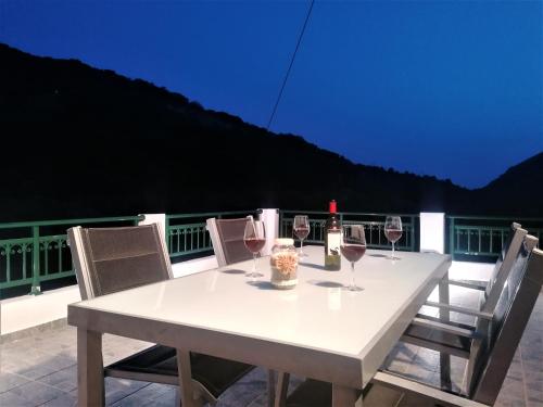 a white table with glasses of wine on a balcony at Villa Araxovoli in Palaiochora