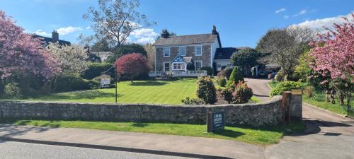 a house with a stone wall and a sign in front of it at CREAG DHUBH COUNTRY HOUSE in Inveraray
