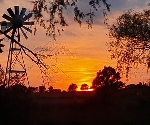 a sunset with a windmill in a field at Teeny Tiny Tipi lakeside pod in Clare
