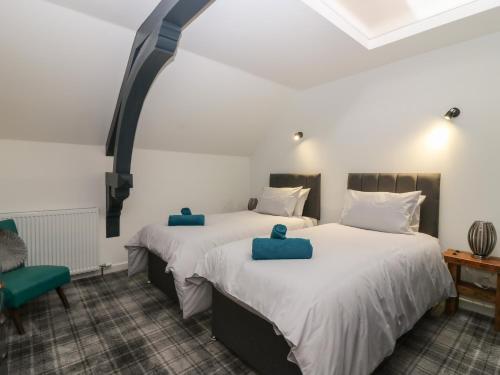 two beds in a room with two blue cushions at The Reception Room at The Institute Executive Apartments in Keith