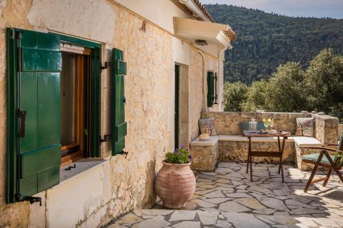 an outdoor patio with a table and a window at Traditional Stone House Anofli 1843 Fiskardo Kefalonia in Fiskardho