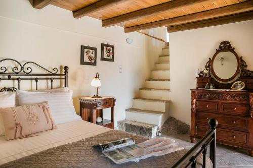 a bedroom with a bed with a dresser and a mirror at Traditional Stone House Anofli 1843 Fiskardo Kefalonia in Fiskardho