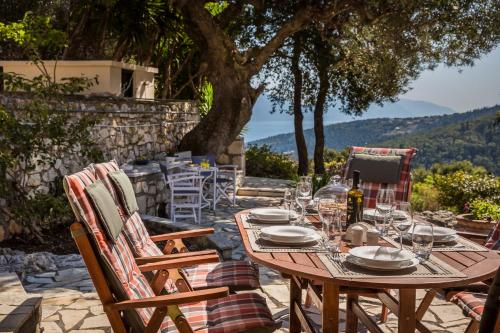 a wooden table with plates and wine glasses at Traditional Stone House Anofli 1843 Fiskardo Kefalonia in Fiskardho