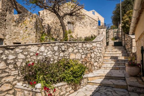 a stone retaining wall with stairs and flowers at Traditional Stone House Anofli 1843 Fiskardo Kefalonia in Fiskardho