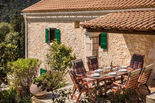 a table and chairs in front of a stone house at Traditional Stone House Anofli 1843 Fiskardo Kefalonia in Fiskardho
