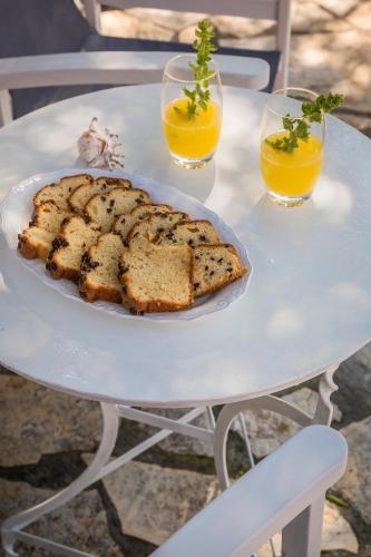 a table with a plate of bread and two glasses of orange juice at Traditional Stone House Anofli 1843 Fiskardo Kefalonia in Fiskardho