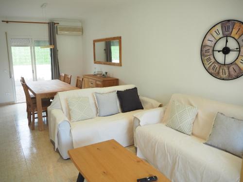 a living room with two couches and a clock on the wall at Casa a L’Escala, piscina comunitaria, Mallols in L'Escala