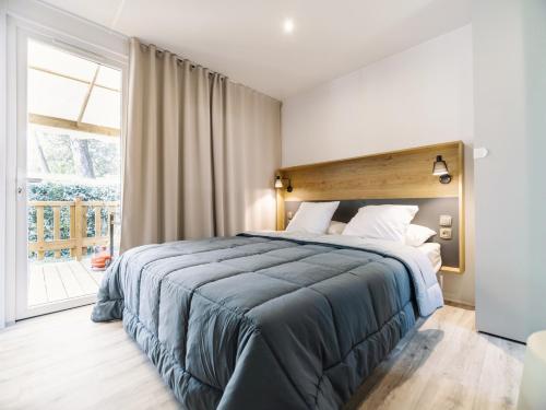 a bedroom with a large bed and a large window at Camping Paradis 4 étoiles Au Port de L'Houmeau - La Rochelle in LʼHoumeau