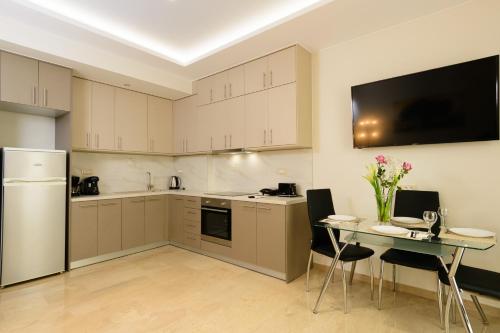 een keuken met witte kasten en een tafel en een tv bij Melia deluxe apartment in Agios Nikolaos