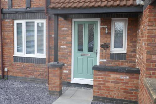a brick house with a green door and windows at Tranquil 3 bedroom town house with Sky Sports in Thornton