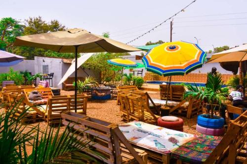 a patio with tables and chairs and umbrellas at Villa Tenko in Ouagadougou