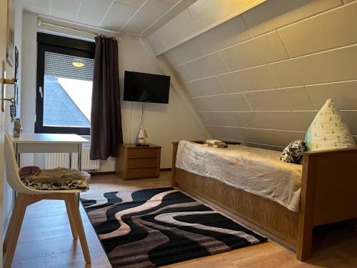 een slaapkamer met een bed, een bureau en een televisie bij Ferienappartements Dolgesheim 2 in Dolgesheim