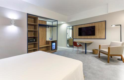 a bedroom with a bed and a table and a tv at Novotel Salvador Rio Vermelho in Salvador