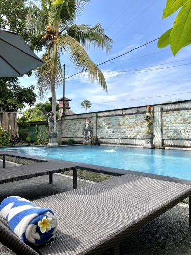 a swimming pool with a bench and a palm tree at PGS HOME STAY in Ubud