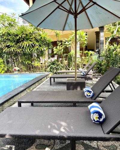 two chairs and an umbrella next to a swimming pool at PGS HOME STAY in Ubud