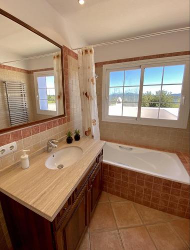 a bathroom with a sink and a tub and a mirror at Villa PALMERA in Sant Jordi